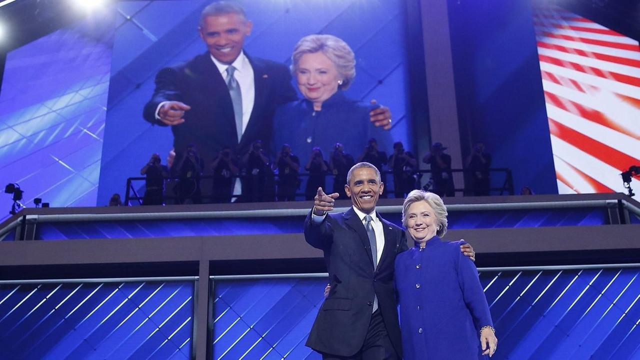 Präsident Barack Obama und Präsidentschaftsbewerberin Hillary Clinton umarmen sich auf dem Parteitag der US-Demokraten und winken den Delegierten zu Präsident Barack Obama und Präsidentschaftsbewerberin Hillary Clinton umarmen sich auf dem Parteitag der US-Demokraten und winken den Delegierten zu
