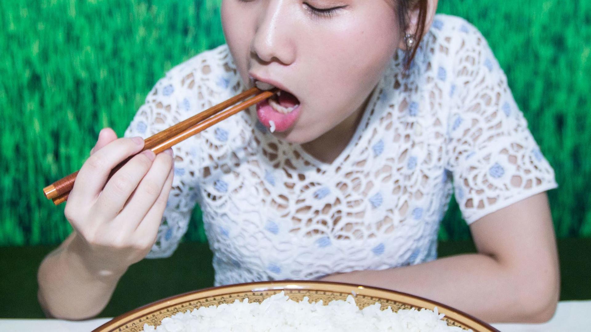 Eine junge Frau isst bei einem Wettbewerb in China Reis aus einer großen Schüssel. Eine junge Frau isst bei einem Wettbewerb in China Reis aus einer großen Schüssel.