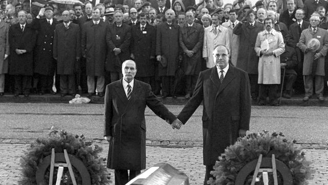Historische Geste: Der französische Staatspräsident Francois Mitterrand (l) und Bundeskanzler Helmut Kohl reichen sich am 22.9.1984 über den Gräbern von Verdun die Hand.
