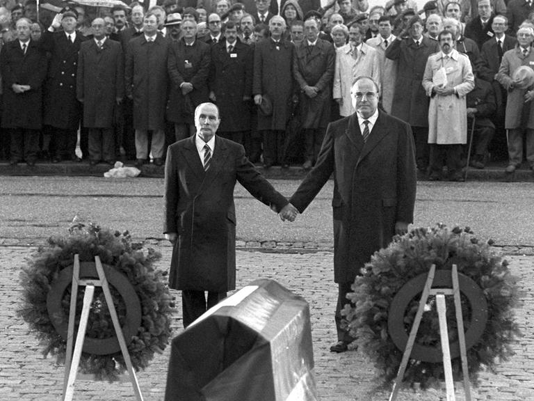 Historische Geste: Der französische Staatspräsident Francois Mitterrand (l) und Bundeskanzler Helmut Kohl reichen sich am 22.9.1984 über den Gräbern von Verdun die Hand.