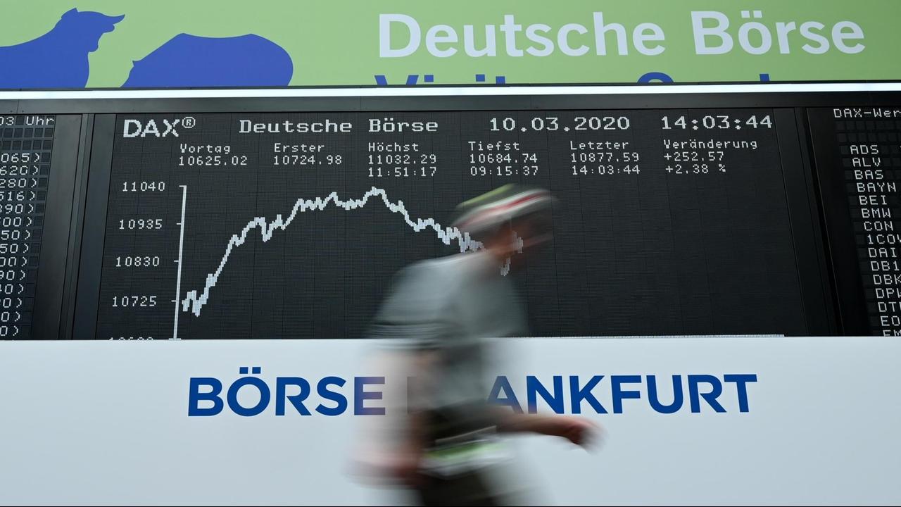 Ein Mann geht im Handelssaal der Frankfurter Wertpapierbörse an der Tafel mit der Dax-Kurve vorbei Ein Mann geht im Handelssaal der Frankfurter Wertpapierbörse an der Tafel mit der Dax-Kurve vorbei