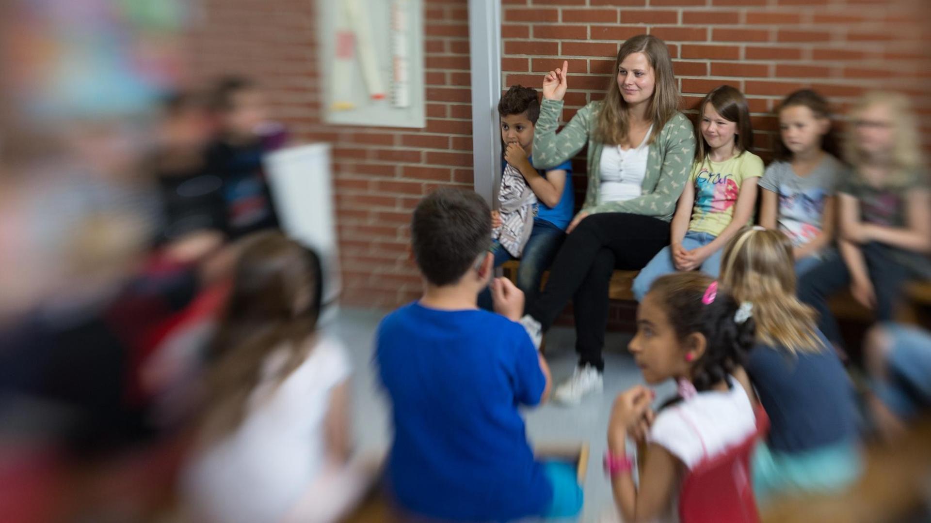 Die Lehrerin Lena Hornbostel sitzt mit Schülern im Kreis. Die Lehrerin Lena Hornbostel sitzt mit Schülern im Kreis.