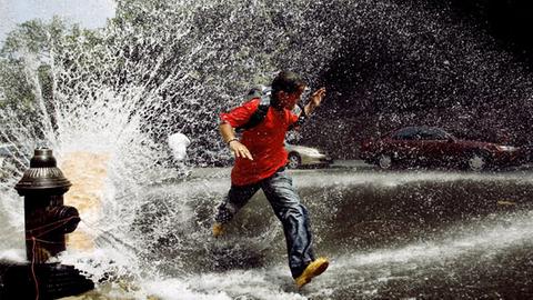 Ein Junge rennt durch die Fontäne eines Feuer-Hydranten in der Bronx, New York.
