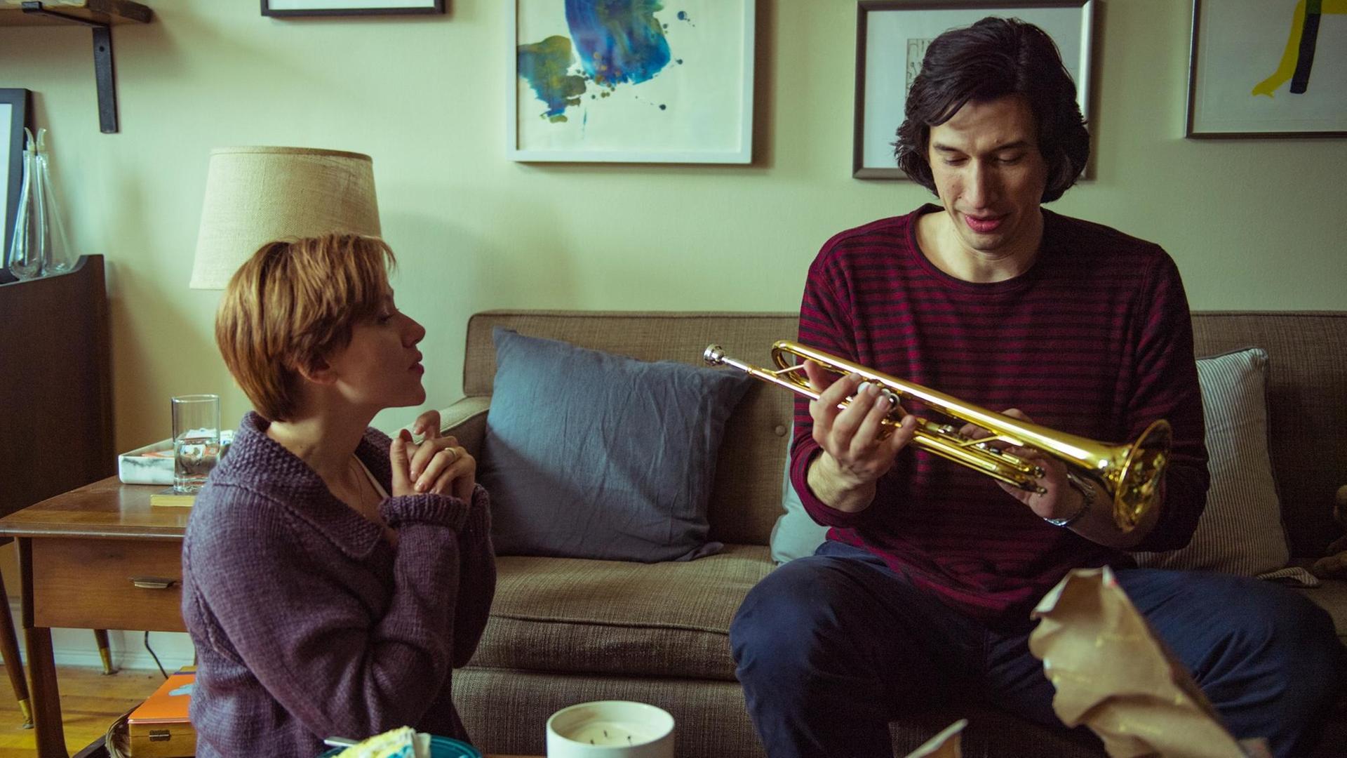 Szene aus dem Film "Marriage Story": Nicole (Scarlett Johansson) und Charlie (Adam Driver) zusammen im Wohnzimmer, er hat eine Trompete in der Hand.
