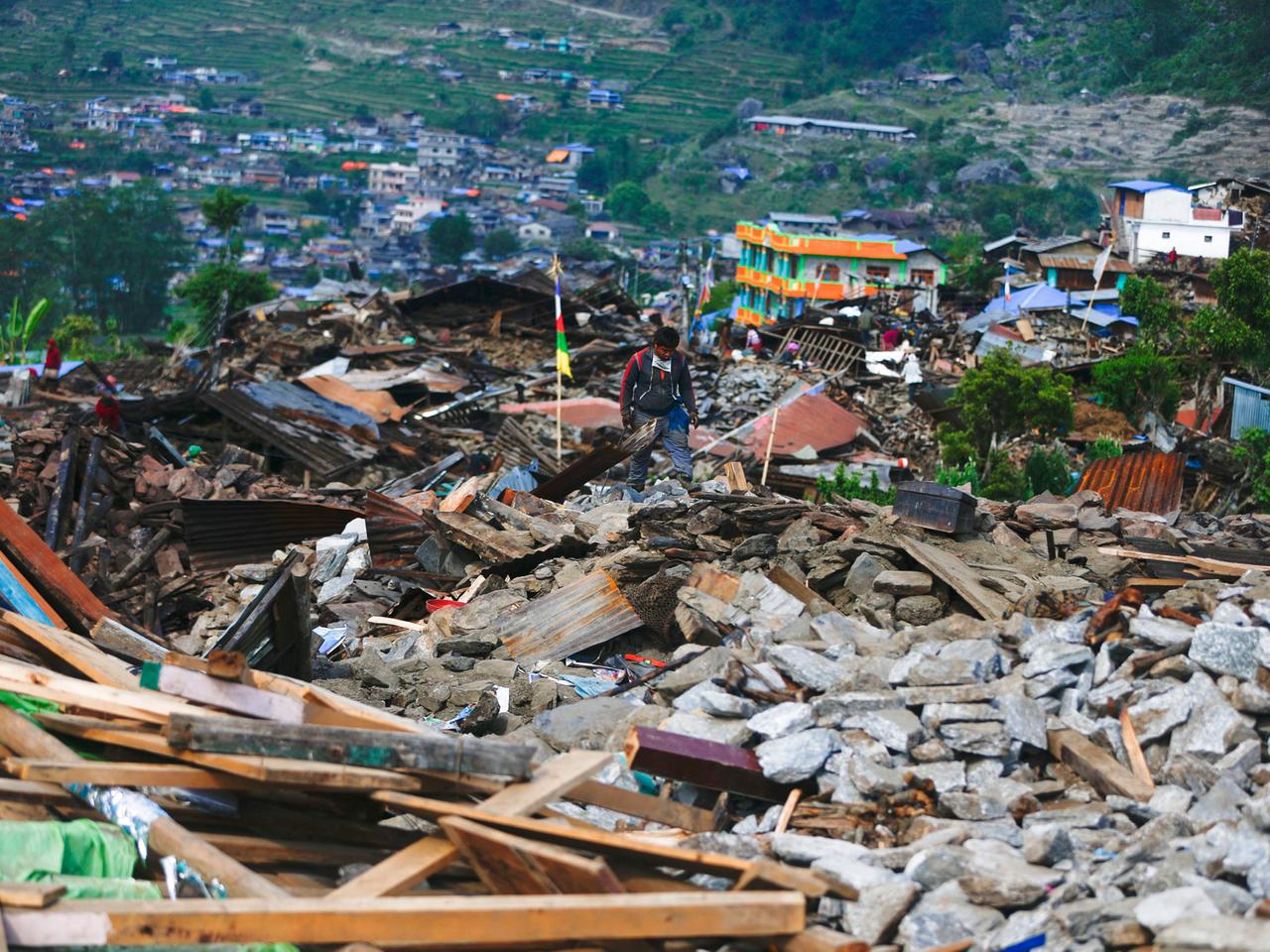 Eine Landschaft, übersät mit Trümmern vieler eingestürzter Häuser, nur noch wenige Gebäude stehen.