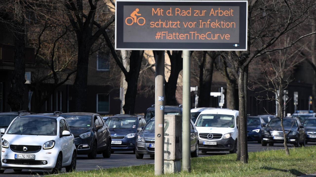 In Berlin wirbt eine Anzeigetafel an einer viel befahrenen Straße dafür mit Rad statt mit dem Auto zu fahren.