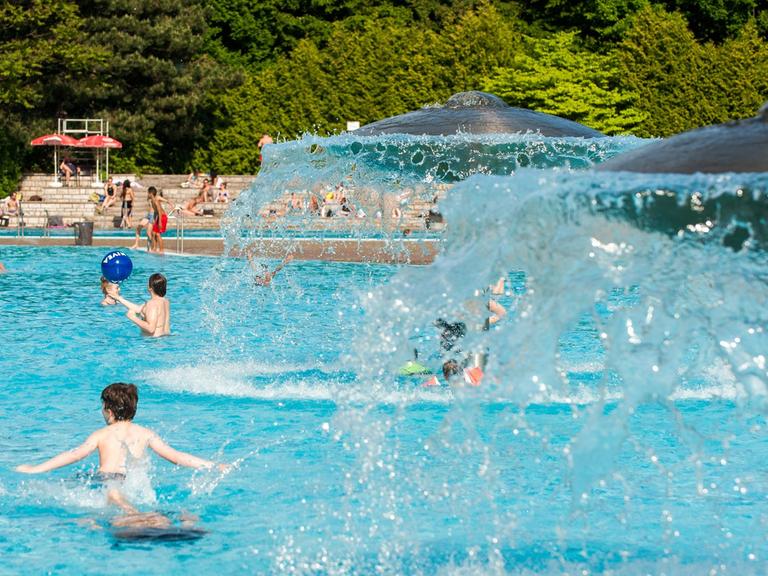 Kinder spielen am 20.05.2014 im Freibad Prinzenbad in Berlin unter pilzförmigen Brunnen.