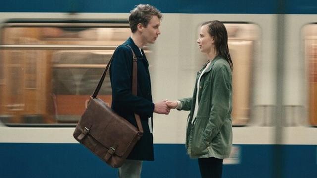 Das Bild zeigt einen Filmstill aus dem Film "Mein Ende. Dein Anfang.", ein Mann und eine Frau stehen einander in der U-Bahn gegenüber und halten einander bei der Hand.
