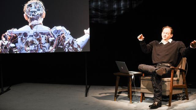 Der Schriftsteller Thomas Melle sitzt neben seinem Avatar auf der Bühne der Münchner Kammerspiele