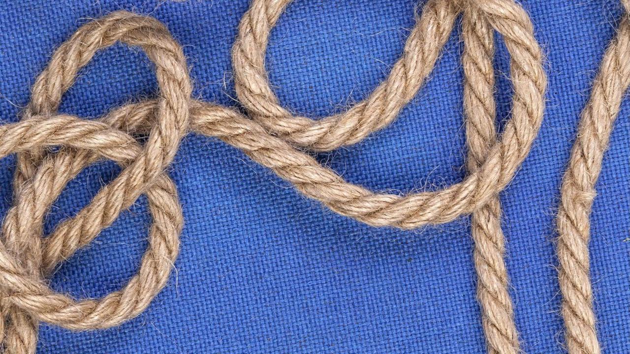 Ein geknotetes Seil vor blauem Hintergrund. Ein geknotetes Seil vor blauem Hintergrund.