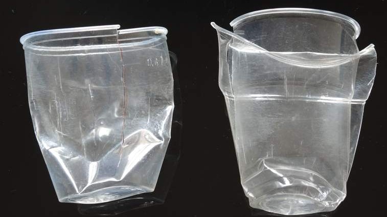 Zwei zerdrückte Plastikbecher liegen nebeneinander Zwei zerdrückte Plastikbecher liegen nebeneinander