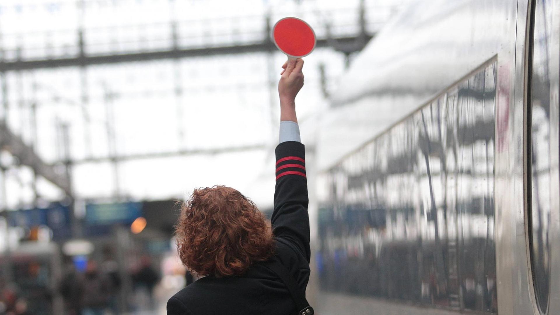 Zugbegleiterin der Deutschen Bahn Fernverkehr fertigt einen abfahrbereiten ICE im Hauptbahnhof Frankfurt ab Zugbegleiterin der Deutschen Bahn Fernverkehr fertigt einen abfahrbereiten ICE im Hauptbahnhof Frankfurt ab