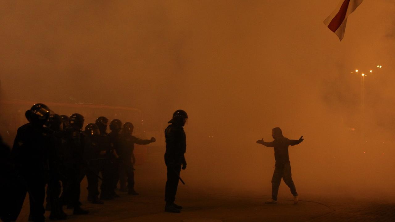 In großen Rauchschwaden veersperren eine Reihe von Polizisten einem Demonstranten den Weg. In großen Rauchschwaden veersperren eine Reihe von Polizisten einem Demonstranten den Weg.