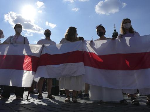Demonstrantinnen und Demonstranten in Prag halten am 7. Juni 2021 gemeinsam die alte belarussische weiß-rot-weiße Nationalflagge.