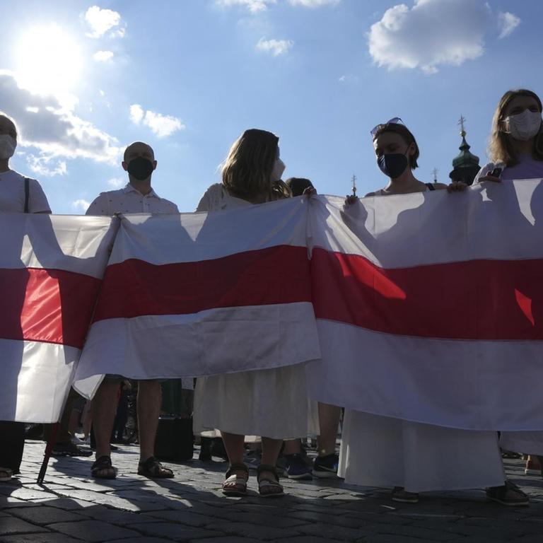 Demonstrantinnen und Demonstranten in Prag halten am 7. Juni 2021 gemeinsam die alte belarussische weiß-rot-weiße Nationalflagge.
