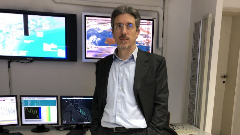 Der Physiker Alvise Papa vor Bildschirmen mit flimmernden Daten von Messstationen und Satelliten
