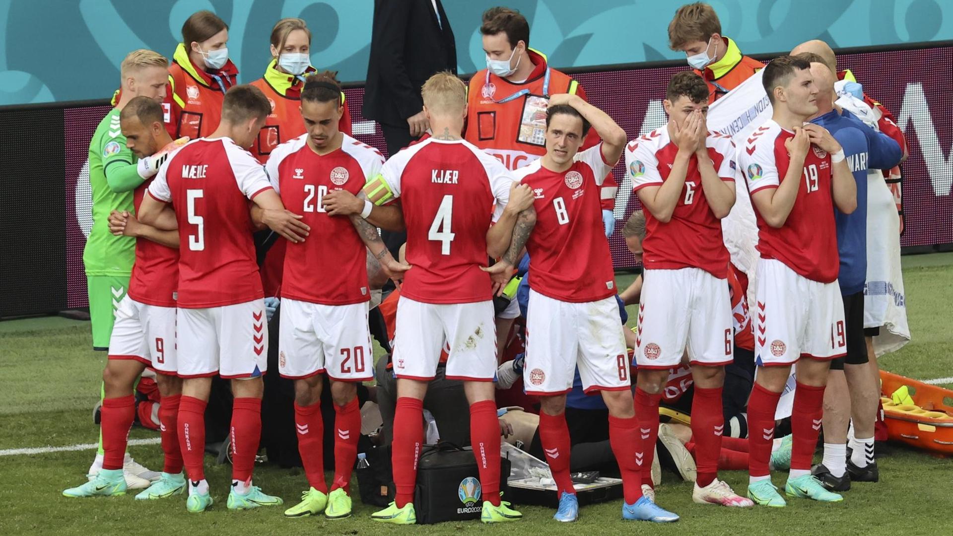 EM-Spiel Dänemark gegen Finnland: Die Mitspieler von Christian Eriksen schirmen ihren Kapitän vor den Kameras und den neugierigen Blicken ab. EM-Spiel Dänemark gegen Finnland: Die Mitspieler von Christian Eriksen schirmen ihren Kapitän vor den Kameras und den neugierigen Blicken ab.