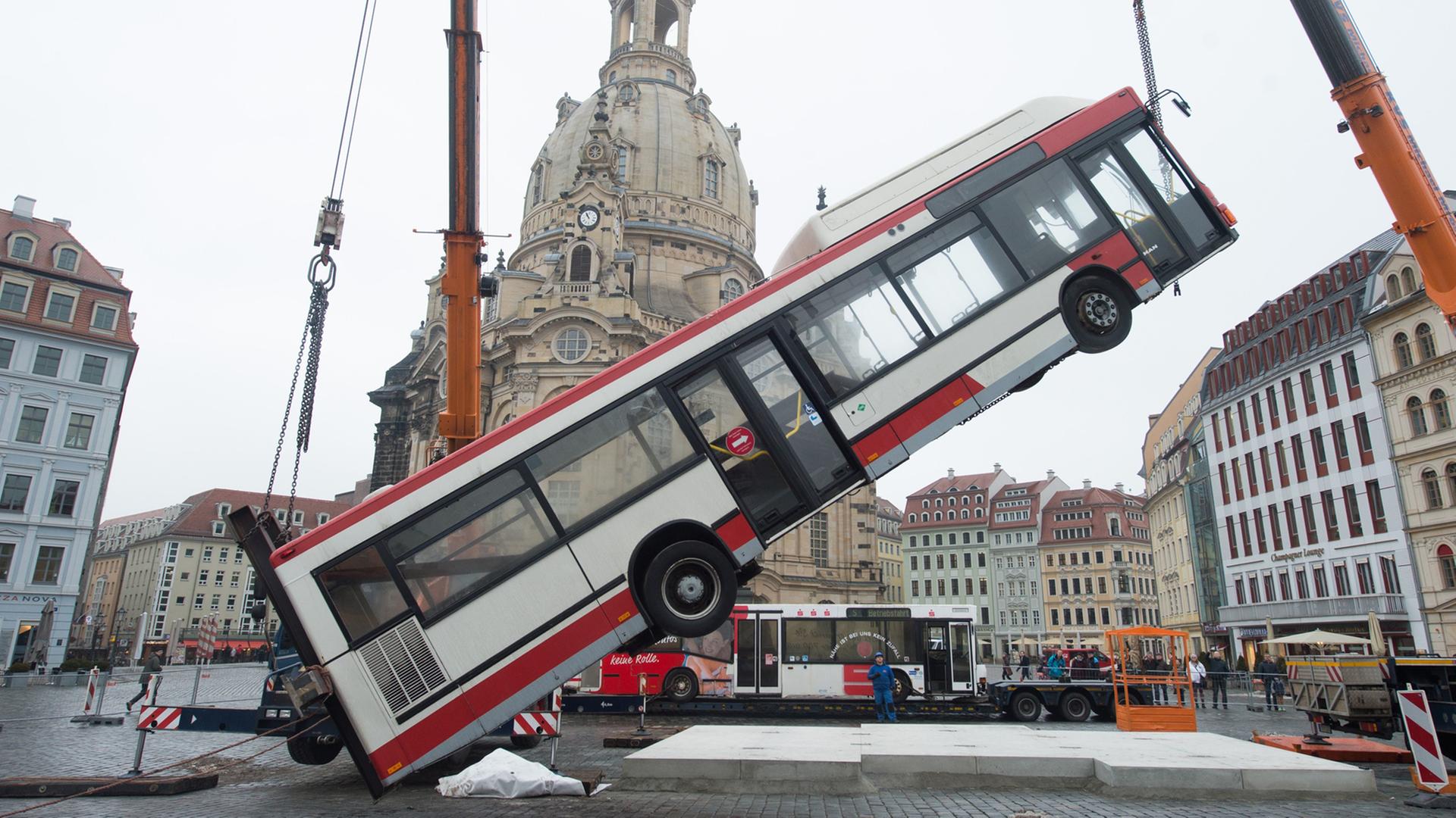 Ein Linienbus wird am 06.02.2017 auf dem Neumarkt vor der Frauenkirche in Dresden von einem Kran in eine senkrechte Position gehoben. Ein Linienbus wird am 06.02.2017 auf dem Neumarkt vor der Frauenkirche in Dresden von einem Kran in eine senkrechte Position gehoben.