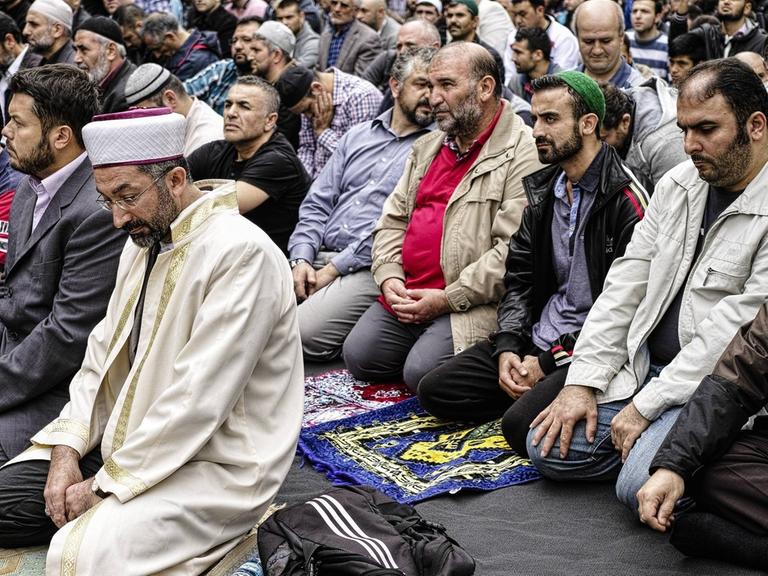 Viele Muslime knien auf dem Boden und sprechen ein Friedensgebet gegen Extremismus in Kreuzberg, Berlin in Deutschland. Islamische Verbände halten Friedensgebet vor der Mevlana-Moschee ab, vor der vor einem Monat ein Brandanschlag verübt wurde. Eine Aktion des Zentralrats der Muslime, der Türkisch-Islamischen Union (Ditib), des Islamrates und dem Verband der Islamischen Kulturzentren (VIKZ).