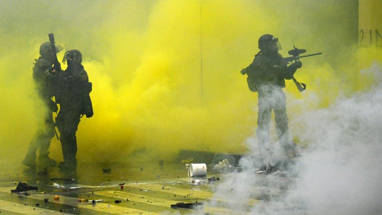 Das Foto zeigt bewaffnete Polizisten in gelbem Rauch bei einem Einsatz auf einer Kundgebung gegen Präsdient Duque in Bogotá/Kolumbien.