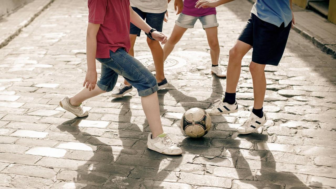 Kinder und Jugendliche spielen Fußball auf der Straße Kinder und Jugendliche spielen Fußball auf der Straße
