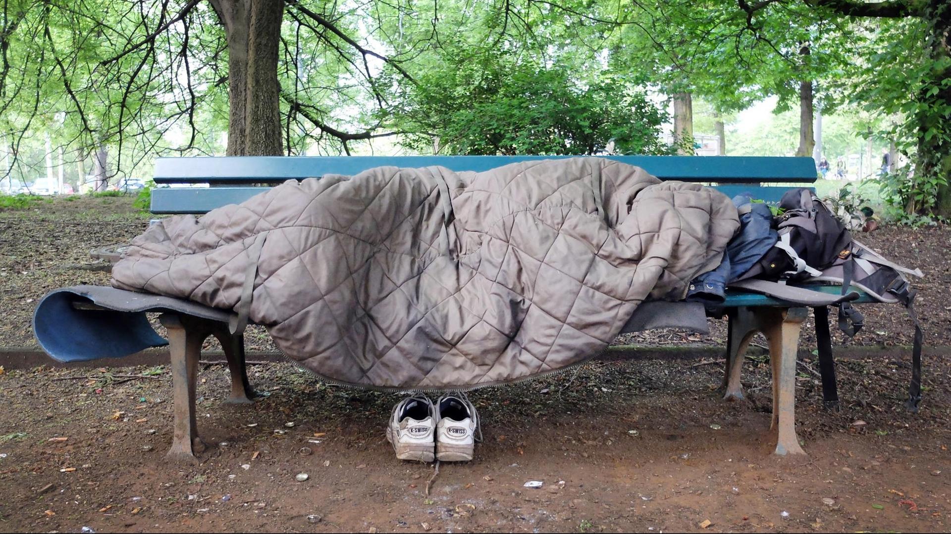Ein Obdachloser schläft auf einer Bank in einem Park in Düsseldorf. Ein Obdachloser schläft auf einer Bank in einem Park in Düsseldorf.