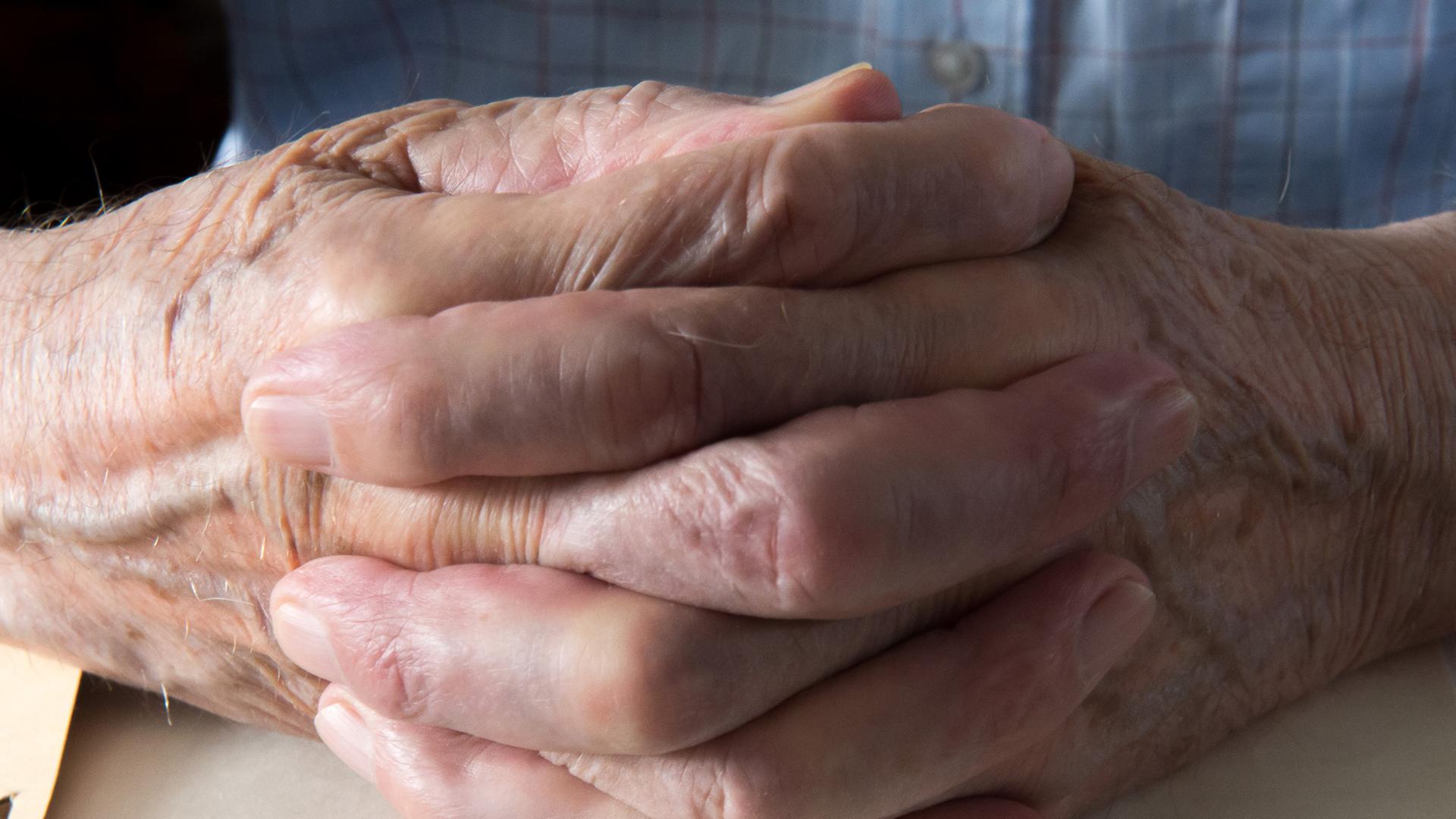 Hände eines Senioren ruhen gefaltet auf einem Rentenbescheid