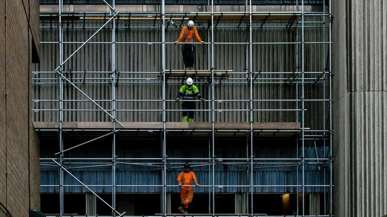 Bauarbeiter stehen an einer Baustelle auf einem Gerüst. Bauarbeiter stehen an einer Baustelle auf einem Gerüst.