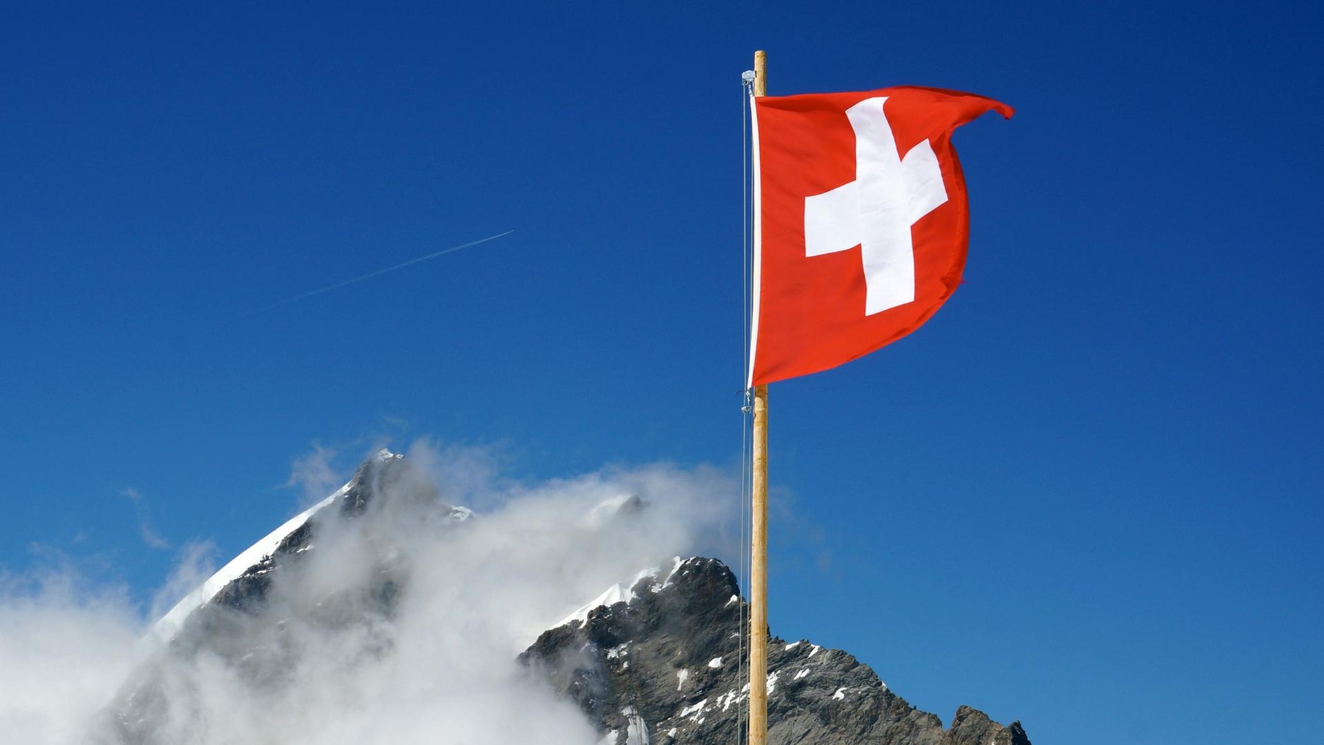 Die Schweizer Flagge weht nahe dem Jungfraujoch in den Berner Alpen in der Schweiz Die Schweizer Flagge weht nahe dem Jungfraujoch in den Berner Alpen in der Schweiz