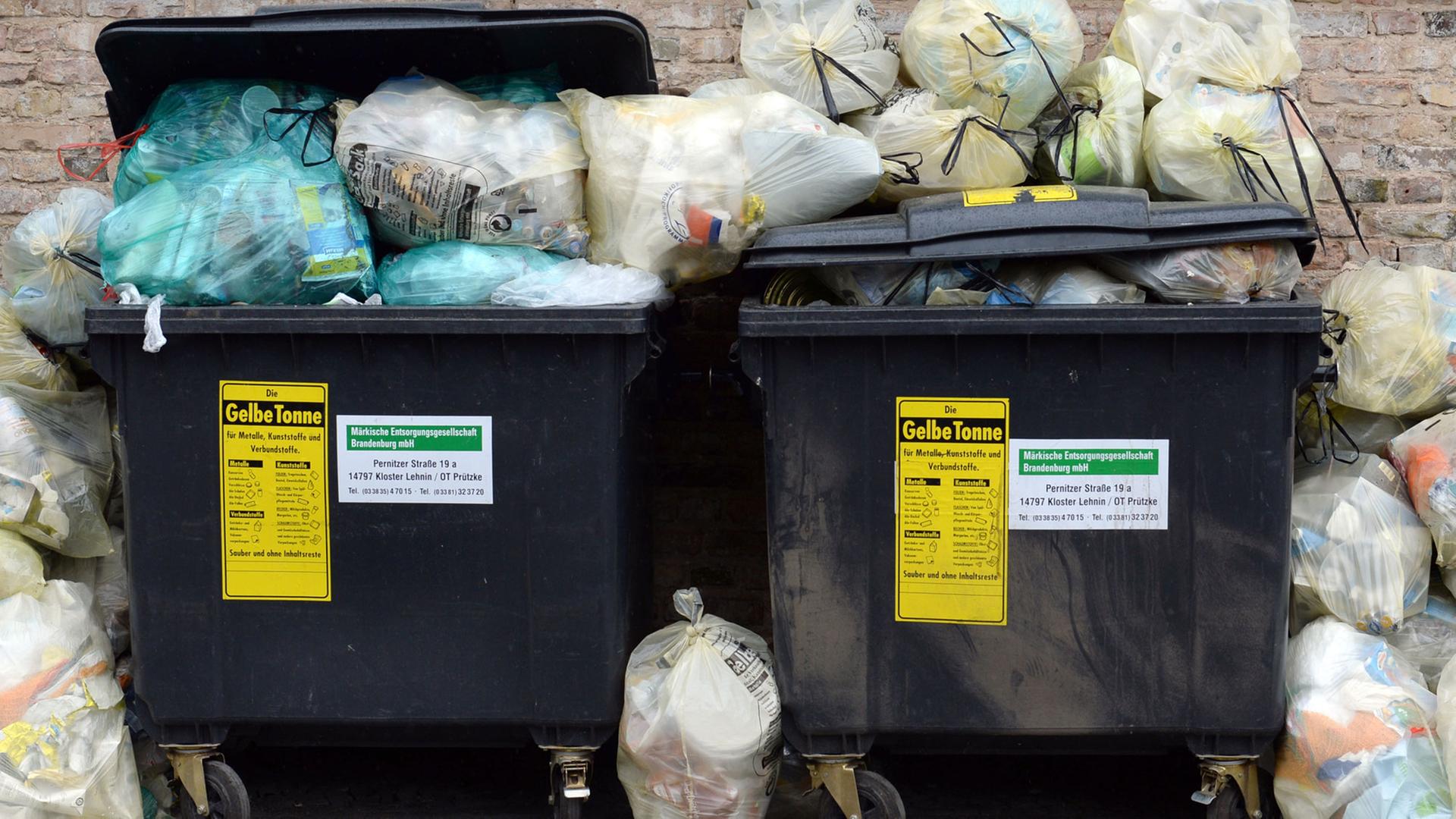 Gelbe Säcke stapeln sich neben entsprechenden Müllcontainern.