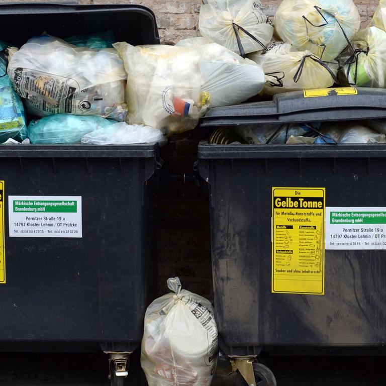 Gelbe Säcke stapeln sich neben entsprechenden Müllcontainern.