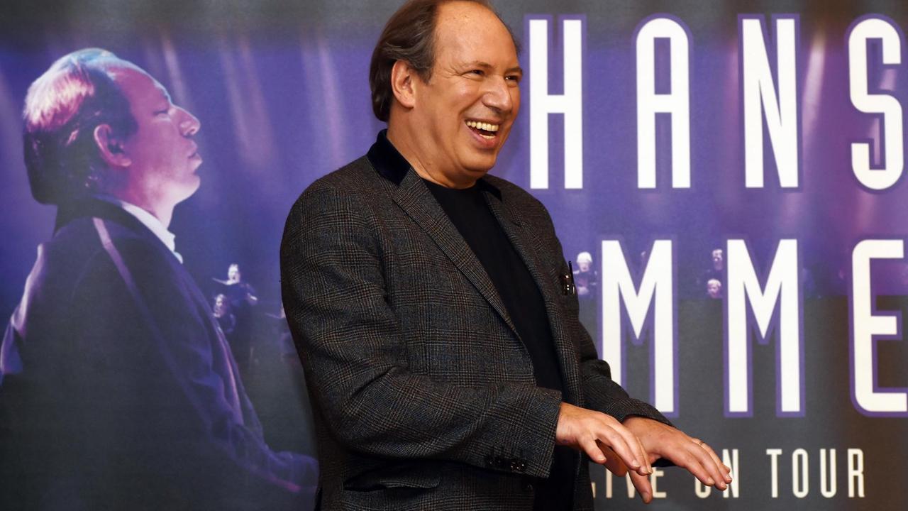 Sie sehen den Filmmusik-Komponisten Hans Zimmer vor einem Plakat, auf dem er auch zu sehen ist. Sie sehen den Filmmusik-Komponisten Hans Zimmer vor einem Plakat, auf dem er auch zu sehen ist.