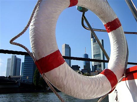 Ein Rettungsring eines kleinen Schiffs ist vor der Skyline mit den Banken in Frankfurt am Main zu sehen. Ein Rettungsring eines kleinen Schiffs ist vor der Skyline mit den Banken in Frankfurt am Main zu sehen.