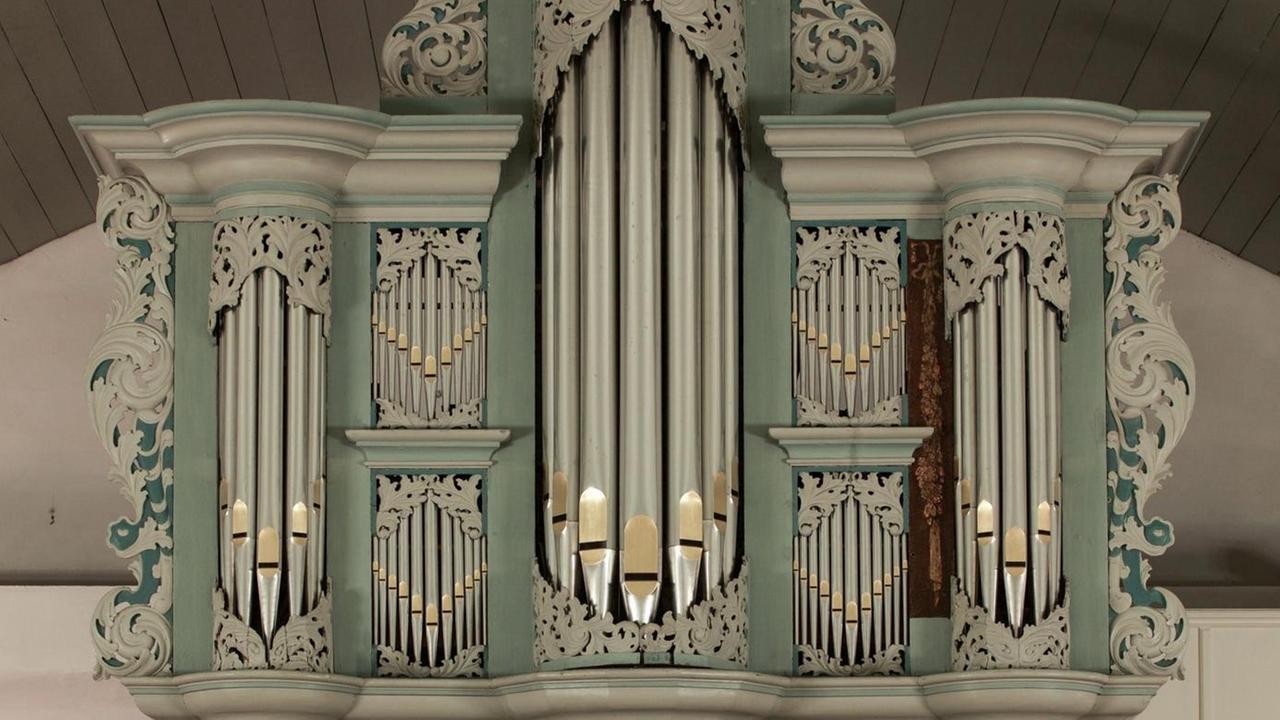 Prospekt einer sogenannten Arp-Schnitger-Orgel mit den großen Orgelpfeifen in der Mitte, eingefügt in grünes und beiges Holz, das aussen girlandenartige Verzierungen aufweist. Prospekt einer sogenannten Arp-Schnitger-Orgel mit den großen Orgelpfeifen in der Mitte, eingefügt in grünes und beiges Holz, das aussen girlandenartige Verzierungen aufweist.