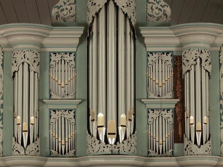 Prospekt einer sogenannten Arp-Schnitger-Orgel mit den großen Orgelpfeifen in der Mitte, eingefügt in grünes und beiges Holz, das aussen girlandenartige Verzierungen aufweist.
