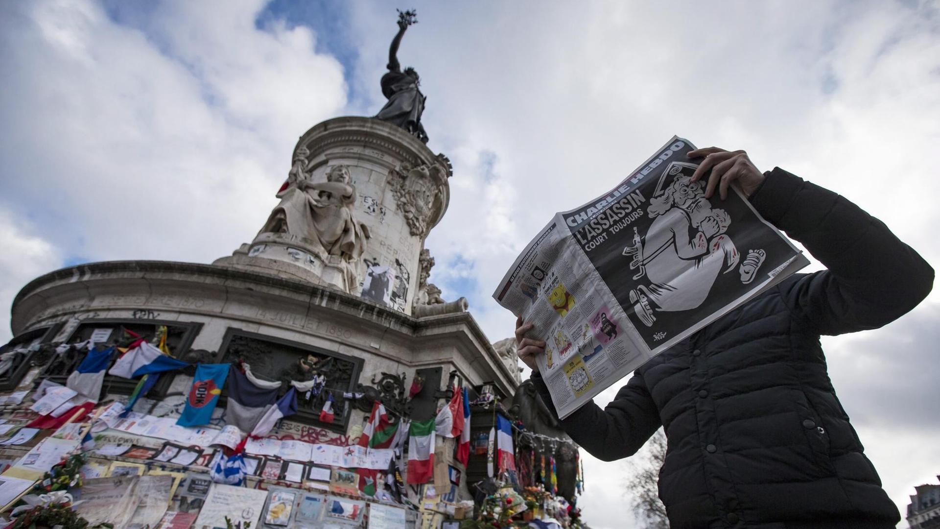 Ein Mann mit der Charlie-Hebdo-Ausgabe zum Jahrestag des Anschlags am Place de la Republique in Paris. Ein Mann mit der Charlie-Hebdo-Ausgabe zum Jahrestag des Anschlags am Place de la Republique in Paris.