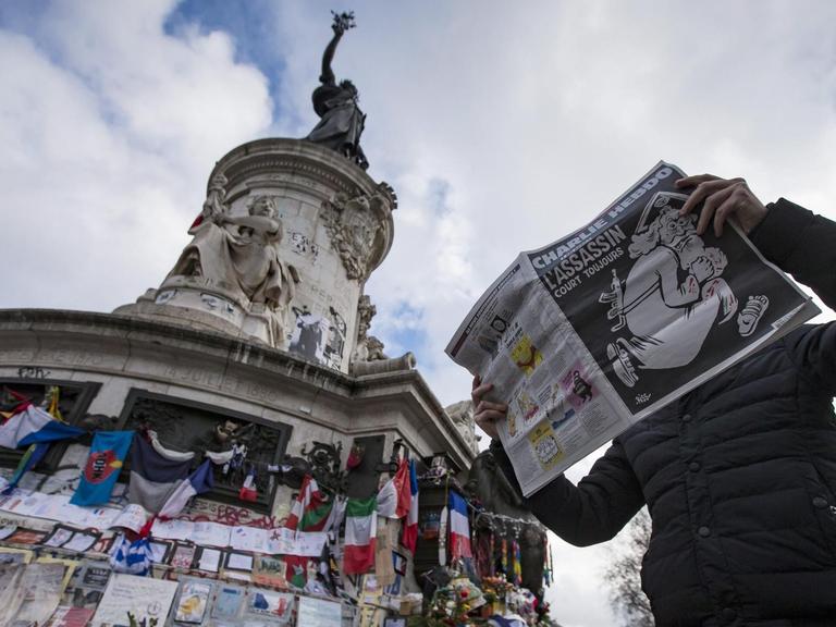 Ein Mann mit der Charlie-Hebdo-Ausgabe zum Jahrestag des Anschlags am Place de la Republique in Paris.