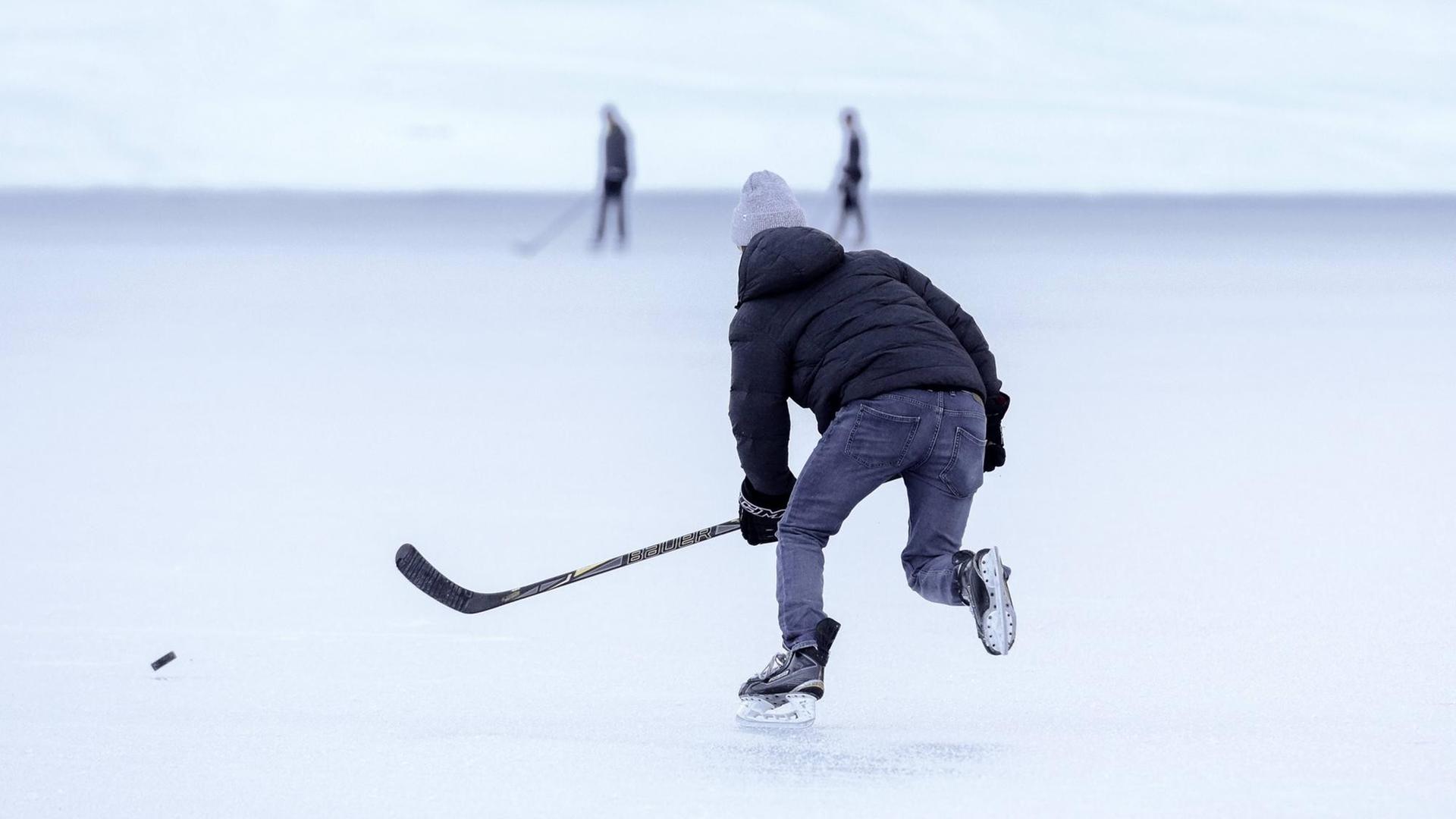Pondhockey-Spieler auf dem zugefrorenen Oeschinensee in der Schweiz. Pondhockey-Spieler auf dem zugefrorenen Oeschinensee in der Schweiz.