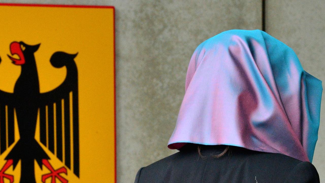 Eine junge Frau mit Kopftuch, die Klägerin, läuft am 24.09.2014 in Erfurt (Thüringen) am Behördenschild mit der Aufschrift "Bundesarbeitsgericht" vorbei. Eine junge Frau mit Kopftuch, die Klägerin, läuft am 24.09.2014 in Erfurt (Thüringen) am Behördenschild mit der Aufschrift "Bundesarbeitsgericht" vorbei.