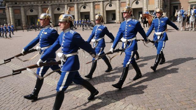 Farbfoto einer energisch ausschreitenden Einheit von Soldaten der schwedischen Königsgarde vor dem Schloss in Stockholm