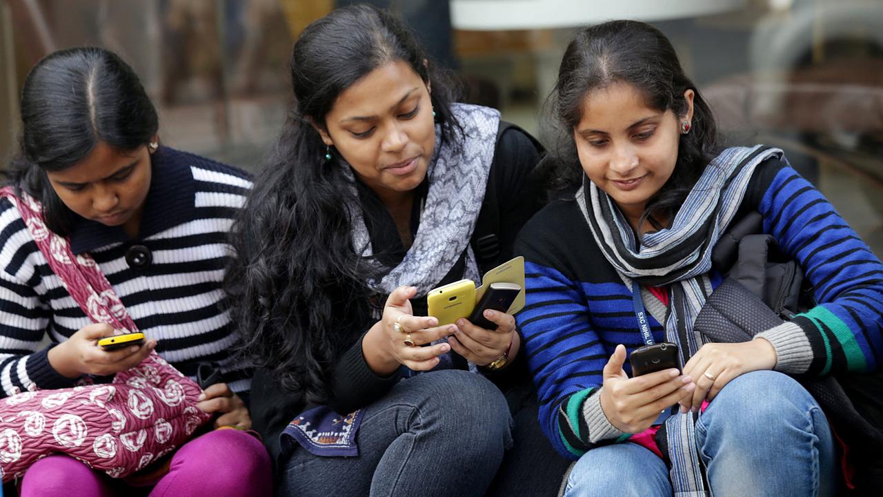 Indische Studentinnen nutzen ihre Smartphones. Aufgenommen 2015 in Kalkutta, Indien 