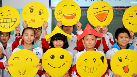 Schüler im chinesischen Xingtai zeigen ihre gemalten Smileys.
