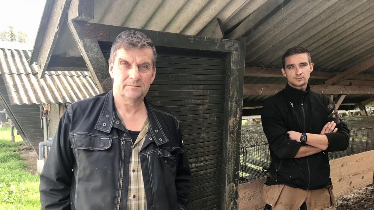 Ein älterer und ein junger Mann stehen am Eingang eines Stalls. Der junge verschränkt vor den Käfigen stehend die Arme. Ein älterer und ein junger Mann stehen am Eingang eines Stalls. Der junge verschränkt vor den Käfigen stehend die Arme.