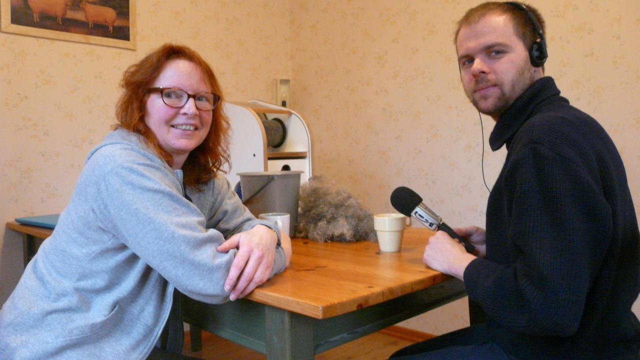 Zu sehen sind rechts der Reporter Johannes Kulms mit Kopfhörern und Mikrofon und links die Interviewpartnerin Helga de Bois. Zu sehen sind rechts der Reporter Johannes Kulms mit Kopfhörern und Mikrofon und links die Interviewpartnerin Helga de Bois.