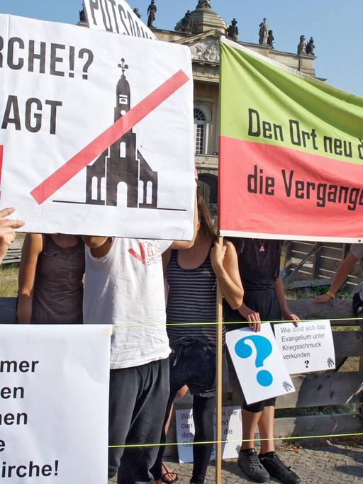 Demonstranten zeigen Transparente, mit denen sie gegen den Wiederaufbau der Potsdamer Garnisonkirche