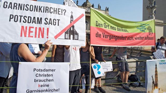 Demonstranten zeigen Transparente, mit denen sie gegen den Wiederaufbau der Potsdamer Garnisonkirche