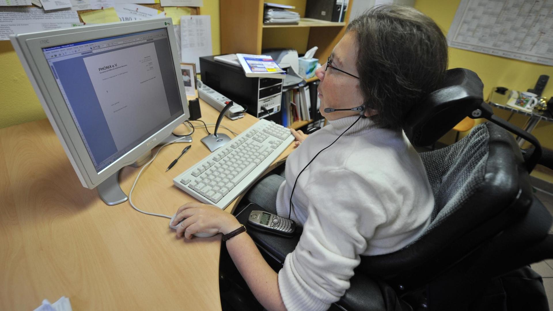 Eine Rollstuhlfahrerin arbeitet am Computer Eine Rollstuhlfahrerin arbeitet am Computer