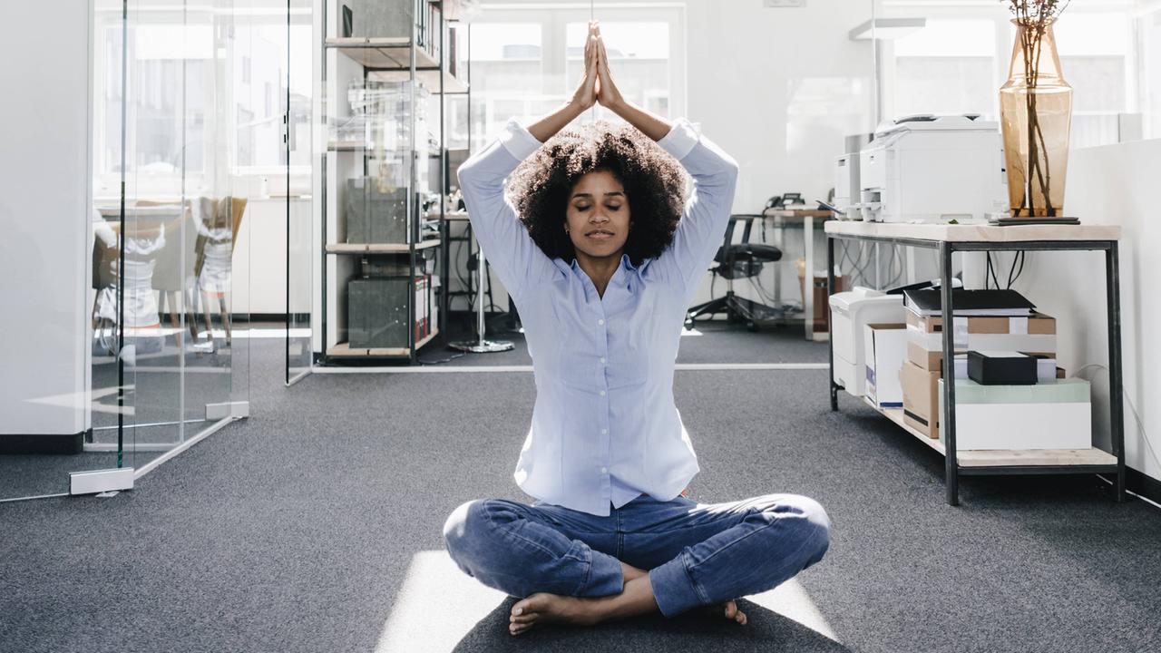 Eine junge Frau beim Yoga in einem Büro Eine junge Frau beim Yoga in einem Büro