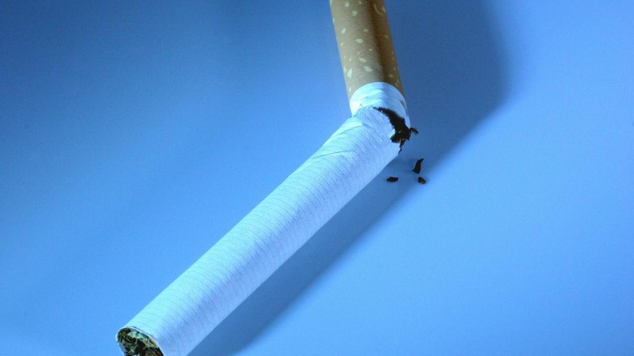 Eine zerbrochene Zigarette vor blauem Hintergrund.