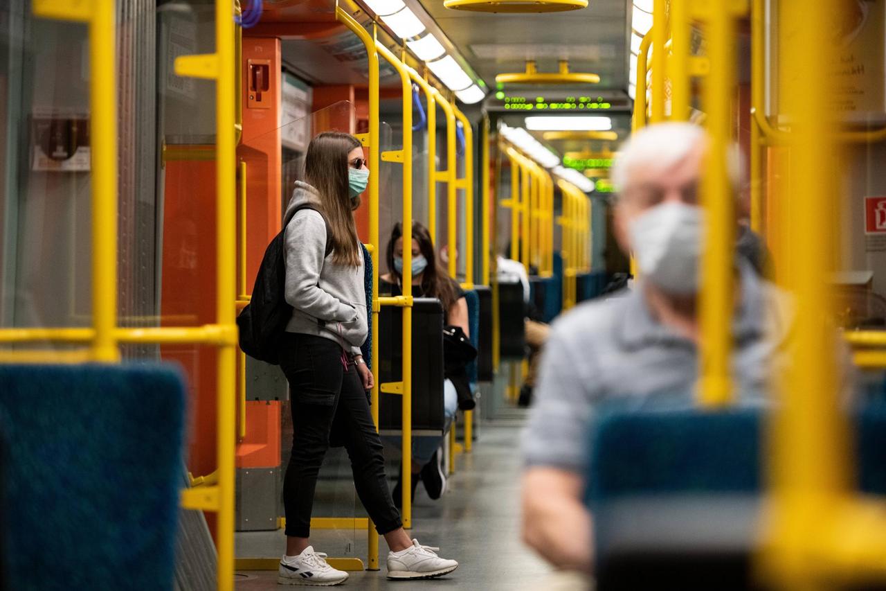 Blick in eine Bahn: Dort sitzen Menschen mit Masken vor dem Gesicht. Blick in eine Bahn: Dort sitzen Menschen mit Masken vor dem Gesicht.